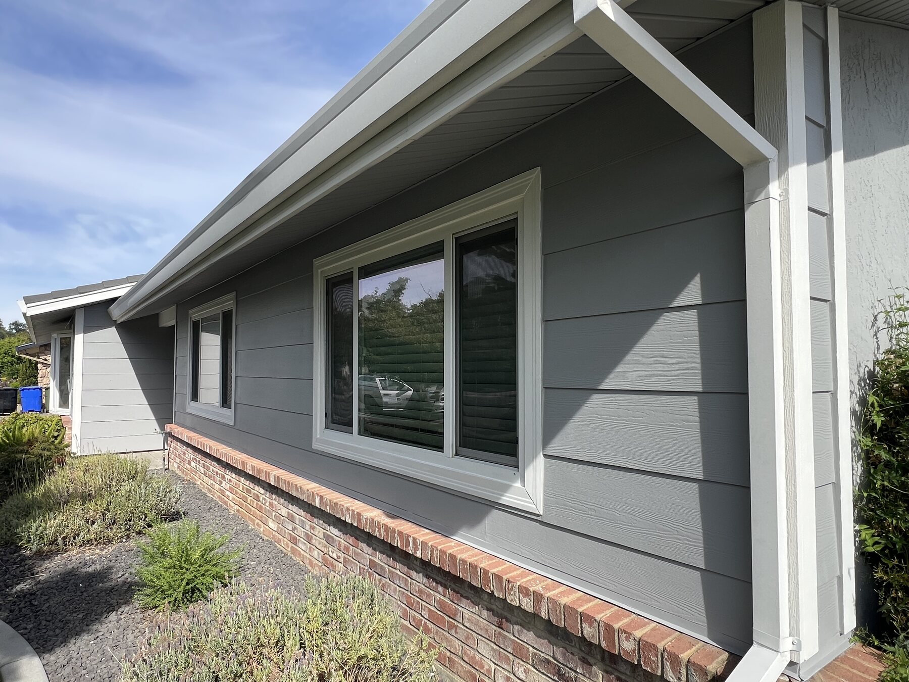 Gray horizontal lap siding with crisp white window and roof trim